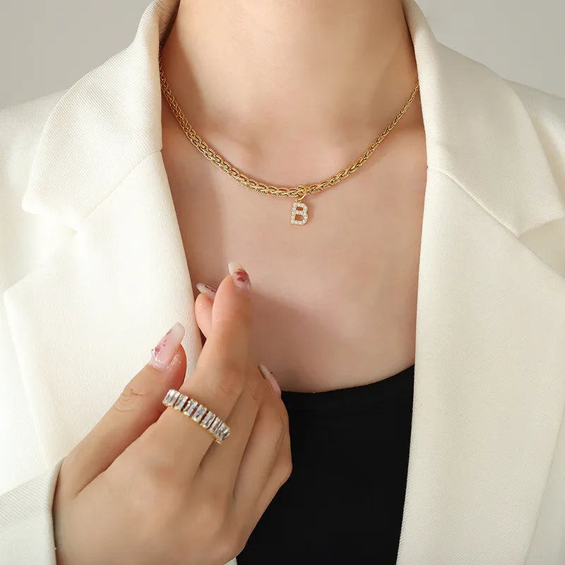Collar con colgante de letra de circonita con incrustaciones de latón