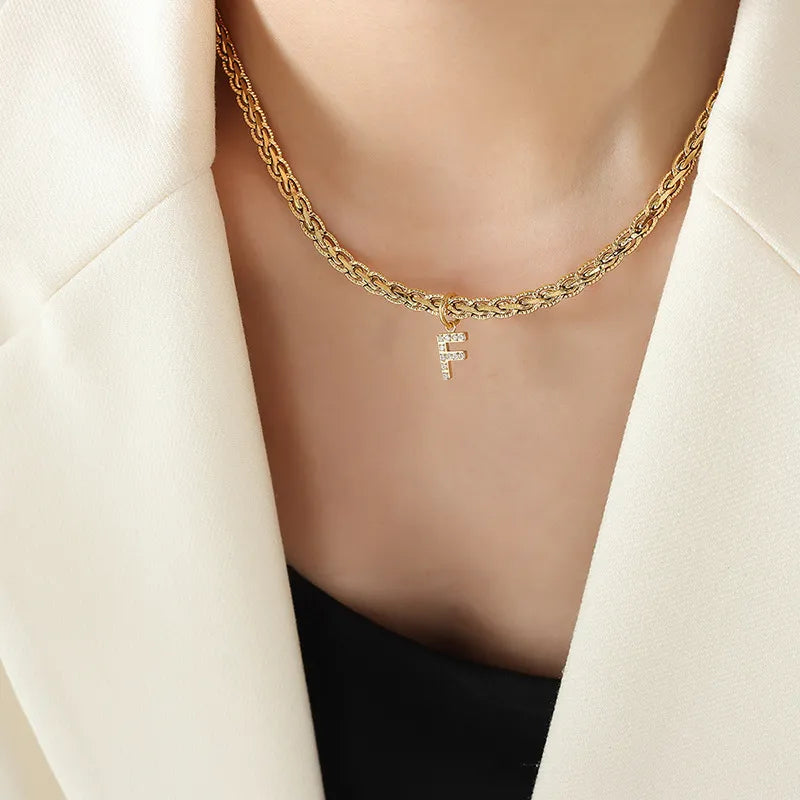 Collar con colgante de letra de circonita con incrustaciones de latón